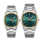 Two matching stainless steel wristwatches with green gradient dials and gold-tone bezels, shown side by side on a white background. Each watch has a metal link bracelet, gold-tone hour markers and hands, and a day-date window.
