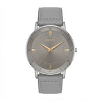A minimalist analog watch with a round silver-tone case, a textured gray dial featuring gold-tone hands and Roman numerals, and a light gray leather strap. The brand name 'Discovery' is printed on the dial.
