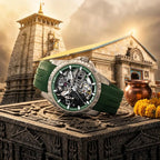 A luxury wristwatch with a green strap and a detailed skeleton dial is displayed in front of a temple structure, with a copper pot and yellow flowers as props.