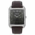 Kenneth Cole Reaction men's watch featuring a square silver-tone case encrusted with clear crystals, a dark charcoal gray dial, and a dark brown alligator leather strap, shown on a white background.
