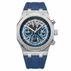 A luxury chronograph watch featuring a brushed stainless steel case, a black dial with blue subdials and silver markers, and a blue silicone strap, shown against a plain white background.