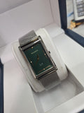 A silver-tone rectangular analog watch with a textured dark green dial and a matching silver mesh strap, displayed inside a white watch box.
