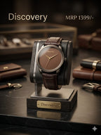 A Discovery wristwatch with a brown leather strap and brown dial, displayed on a black stand with a wooden base labeled 'Discovery'. The watch is set on a dark marble surface with leather accessories blurred in the background.