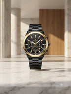 A luxury wristwatch with a black bezel, black dial, and gold-tone accents, displayed on a marble surface in a modern interior setting.