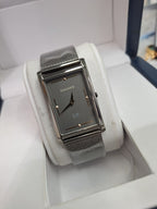 A Discovery SLUM women's watch with a silver-tone rectangular case, textured dark gray dial, and matching silver mesh strap, displayed inside its white presentation box.